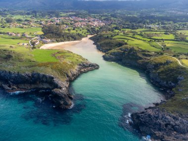 Playa de Poo 'daki hava manzarası, Llanes yakınlarındaki gelgit sırasında, Asturias, Kuzey İspanya' nın yeşil kıyıları, beyaz kumlu plajları, kayalıkları, gizli mağaraları, yeşil tarlaları ve dağları olan.