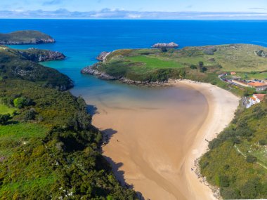 Playa de Poo 'daki hava manzarası, Llanes yakınlarındaki gelgit sırasında, Asturias, Kuzey İspanya' nın yeşil kıyıları, beyaz kumlu plajları, kayalıkları, gizli mağaraları, yeşil tarlaları ve dağları olan.