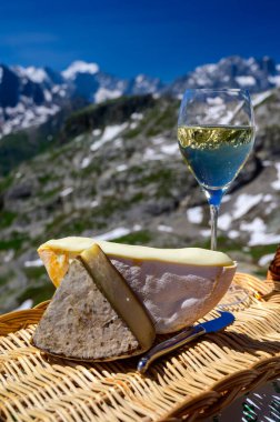 Peynir koleksiyonu, Fransız Alpleri 'ndeki Savoy bölgesinden Reblochon ve Tomme de Savoie peyniri, açık havada hafif inek sütü, Fransız Alpler dağlarının karlı tepelerinde manzara