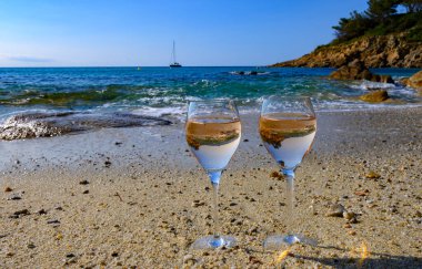 Provence 'de yaz mevsimi, güneşli bir günde Saint-Tropez yakınlarındaki kumlu sahilde iki bardak soğuk gül şarabı, Var Bölümü, Fransa.