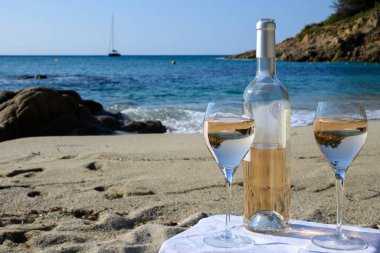 Provence 'de yaz mevsimi, güneşli bir günde Saint-Tropez yakınlarındaki kumlu sahilde iki bardak soğuk gül şarabı, Var Bölümü, Fransa.