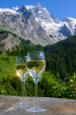 Kuru beyaz Roussette de Savoie ve Savoy bölgesinden Vin de Savoie Fransız şarabı içerken, üzerinde kar olan Hautes Alpes dağları manzaralı