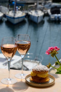 Fransız Rivierası 'nın şarap ve kekleri, bir bardak soğuk gül Cote de Provence şarabı ve Port Grimaud limanında Tarte Tropezienne keki, Fransa' nın Provence şehrinde yaz tatili