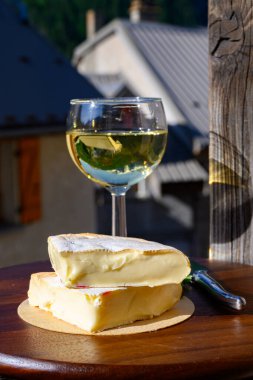 Reblochon Fransız peyniri Haute-Savoie 'de yapıldı, beyaz Roussette de Savoie veya Vin de Savoie şarabı eski Alripne köyü ve Hautes Alpes dağlarının tepelerinde kar manzaralı