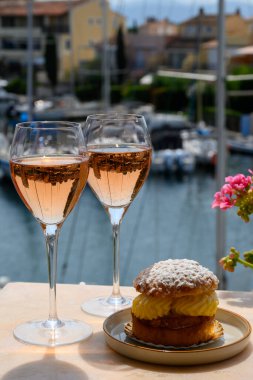 Fransız Rivierası 'nın şarap ve kekleri, bir bardak soğuk gül Cote de Provence şarabı ve Port Grimaud limanında Tarte Tropezienne keki, Fransa' nın Provence şehrinde yaz tatili