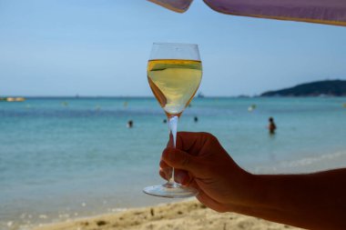 Provence 'de yaz zamanı, Pampelonne' da bir bardak soğuk beyaz şarap güneşli bir günde Saint-Tropez yakınlarındaki kumlu plajda, Var Bölümü, Fransa.