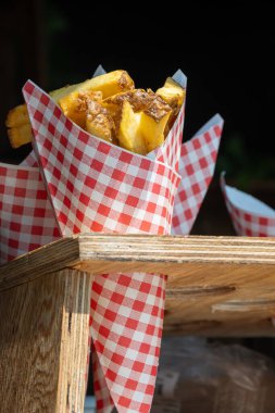 Traditional street food in Belgium and Netherlands, French fried potatoes chips with mayonnaise sauce in paper cone bag.