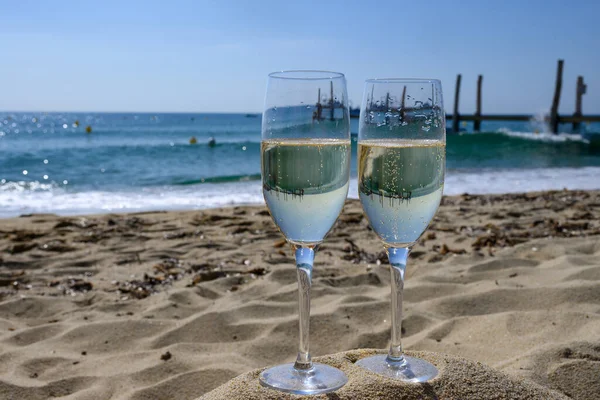 Provence 'de yaz mevsimi, iki bardak soğuk şampanya krep şarabı güneşli bir günde Saint-Tropez yakınlarındaki ünlü Pampelonne kumlu plajında, Var Bölümü, Fransa' da vanation