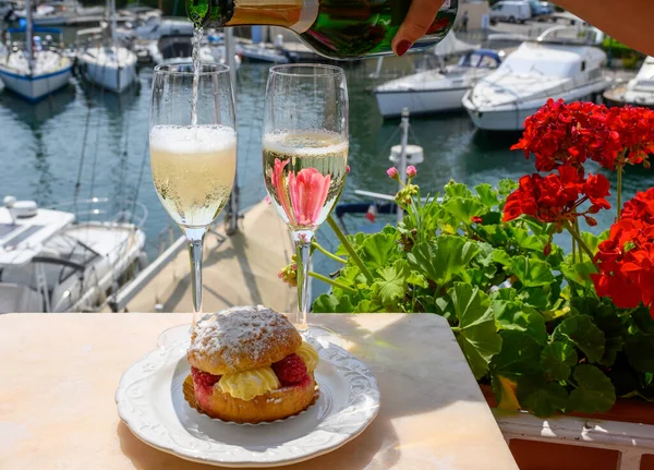 stock image Drinking of French brut champagne sparkling wine with cake Tarte Tropezienne, club party in yacht harbour of Port Grimaud near Saint-Tropez, French Riviera vacation, Var, France