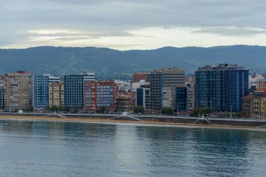 Gijon, Asturias, İspanya 'daki gezinti güvertesi, evler ve San Lorenzo plajına bakın.