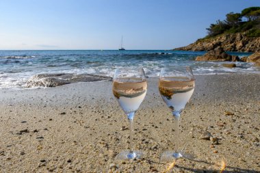 Provence 'de yaz mevsimi, güneşli bir günde Saint-Tropez yakınlarındaki kumlu sahilde iki bardak soğuk gül şarabı, Var Bölümü, Fransa.