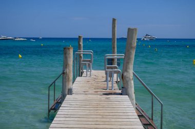 Ramatuelle ve Saint-Tropez yakınlarındaki efsanevi Pampelonne sahilinin ahşap iskelesi ve berrak mavi suyu, Fransa 'nın Riviera kentinde yaz tatili.