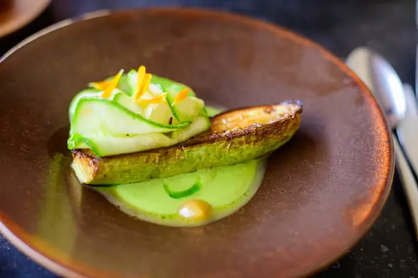 Exquisite vegetarian zucchini dish of modern French haute cuisine prepared with fresh organic ingredients from restaurant own garden and farm and beautifully served with sauce