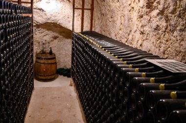 Yeraltındaki mağaralarda, ahşap raflarda şişelerle yürüyoruz. Geleneksel şampanya yapımı Chardonnay ve Epernay, Champagne, France 'da siyah üzümler.