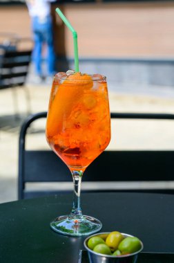 Garson Aperol Sprits yaz kokteylini Aperol, Prosecco, buz küpleri, tonik su ve portakalla hazırladı, güneşli terasta içmeye hazır.