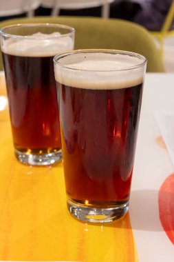 Eski İngiliz barında servis edilen soğuk taze İngiliz IPA birası ve bira bardakları koyu arka planda.