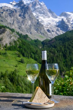 Peynir ve şarap, Savoy bölgesinden beyaz Roussette de Savoie ve Vin de Savoie şarabı ve yazın üstleri karlı Hautes Alpes dağları manzaralı..