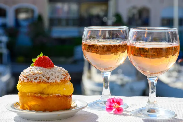 Wine and cakes of French Riviera, glasses of cold rose Cote de Provence wine and Tarte Tropezienne cake in yacht harbour of Port Grimaud, summer vacation  in Provence, France