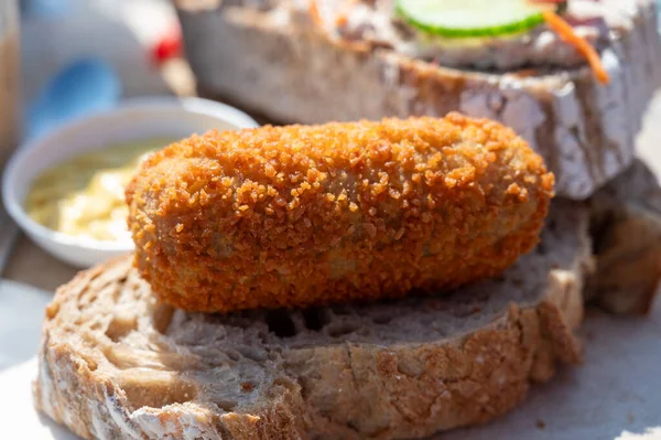 Dutch fast food, deep fried croquettes filled with ground beef meat served on bread, close up