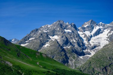 Dağlar ve yeşil alp çayırları Col du Lautaret, Massif des Ecrins, Hautes Alpes, Fransa yakınlarındaki yazlık alanları