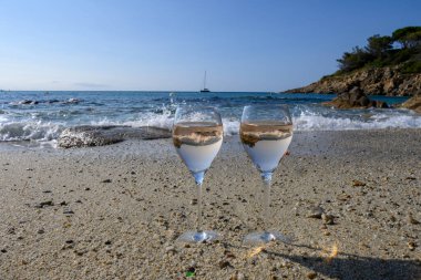 Provence 'de yaz mevsimi, güneşli bir günde Saint-Tropez yakınlarındaki kumlu sahilde iki bardak soğuk gül şarabı, Var Bölümü, Fransa.