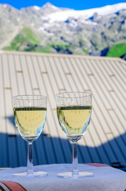 Kuru beyaz Roussette de Savoie ve Savoy bölgesinden Vin de Savoie Fransız şarabı içerken, üzerinde kar olan Hautes Alpes dağları manzaralı