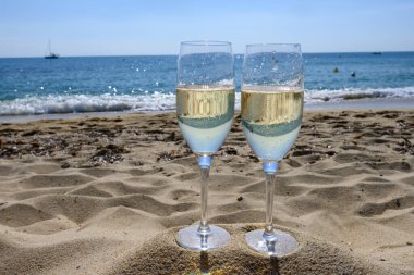 Provence 'de yaz mevsimi, iki bardak soğuk şampanya krep şarabı güneşli bir günde Saint-Tropez yakınlarındaki ünlü Pampelonne kumlu plajında, Var Bölümü, Fransa' da vanation