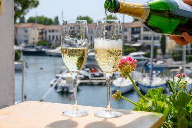 Fransız brüt şampanyası bardaklarda köpüklü şarap içmek, Saint-Tropez yakınlarındaki Port Grimaud limanında kulüp partisi, Fransız Riviera tatili, Var, Fransa
