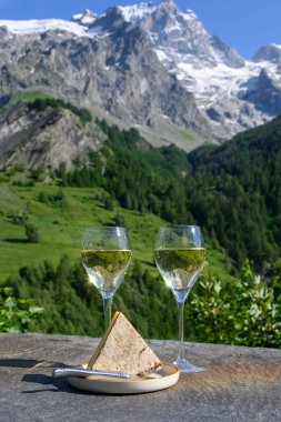 Peynir ve şarap, Savoy bölgesinden beyaz Roussette de Savoie ve Vin de Savoie şarabı ve üstünde karlı Hautes Alpes Dağları manzaralı.