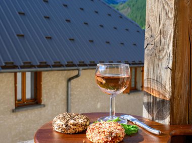 Peynir ve şarap, bir bardak kuru gül şarabı ve biber soslu taze keçi peyniri, üzerinde kar olan Hautes Alpes dağlarının manzarası