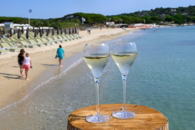 Provence 'de yaz mevsimi, iki bardak soğuk şampanya krep şarabı güneşli bir günde Saint-Tropez yakınlarındaki ünlü Pampelonne kumlu plajında, Var Bölümü, Fransa' da vanation