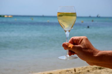 Provence 'de yaz zamanı, Pampelonne' da bir bardak soğuk beyaz şarap güneşli bir günde Saint-Tropez yakınlarındaki kumlu plajda, Var Bölümü, Fransa.