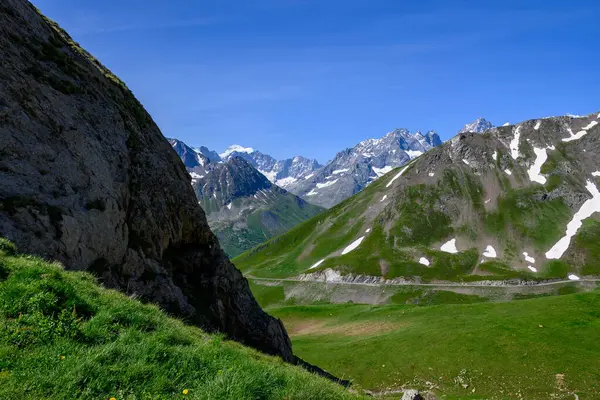 Col de Lautaret 'ten Col du Calibier' e, Dağlar 'a ve yazın Massif des Ecrins, Hautes Alpes, Fransa' nın yeşil dağlık manzarasına dar dağlar.