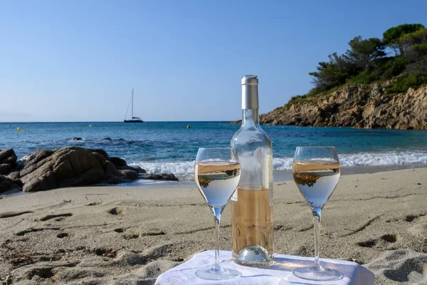 Summer time in Provence, two glasses of cold rose wine on sandy beach near Saint-Tropez in sunny day, Var department, France.