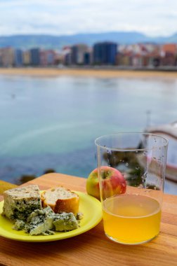 Asturias 'ta yiyecek eşleşmesi, Arenas' taki mağaralardan gelen mavi inek kabukları, açık havada bir cam elma şarabı ve İspanya 'nın Gijon kentindeki San Lorenzo plajında manzara sunuyor.