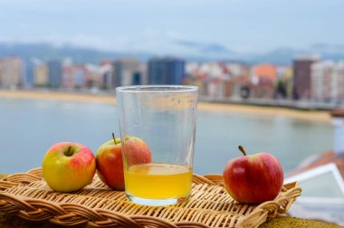 Tahta fıçıdaki mayalanmış elmalardan yapılan geleneksel Asturian şarabı hava kabarcıkları için büyük bir yükseklikten San Lorenzo sahilindeki içecek ve manzaraya dökülmelidir.