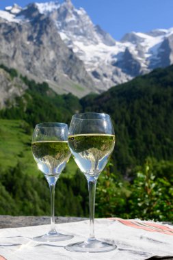 Kuru beyaz Roussette de Savoie ve Savoy bölgesinden Vin de Savoie Fransız şarabı içerken, üzerinde kar olan Hautes Alpes dağları manzaralı