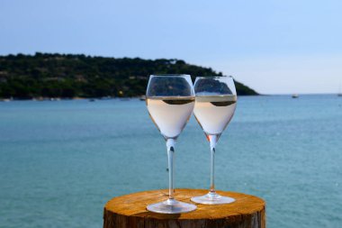 Provence 'de yaz mevsimi, güneşli bir günde Saint-Tropez yakınlarındaki Pampelonne kumsalında iki bardak soğuk gül şarabı, Var Bölümü, Fransa.