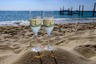 Provence 'de yaz mevsimi, iki bardak soğuk şampanya krep şarabı güneşli bir günde Saint-Tropez yakınlarındaki ünlü Pampelonne kumlu plajında, Var Bölümü, Fransa' da vanation