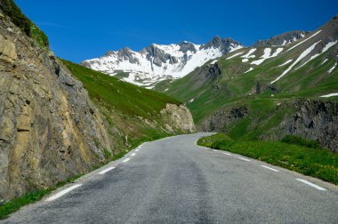 Narrow mountains road from Col de Lautaret to Col du Calibier, Mountains and green alpine meadows views of Massif des Ecrins, Hautes Alpes, France in summer clipart