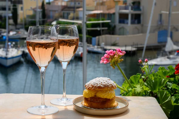 Wine and cakes of French Riviera, glasses of cold rose Cote de Provence wine and Tarte Tropezienne cake in yacht harbour of Port Grimaud, summer vacation  in Provence, France