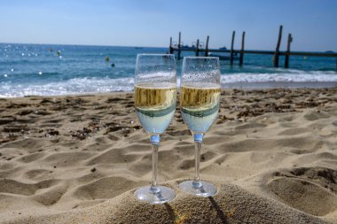 Provence 'de yaz mevsimi, iki bardak soğuk şampanya krep şarabı güneşli bir günde Saint-Tropez yakınlarındaki ünlü Pampelonne kumlu plajında, Var Bölümü, Fransa' da vanation