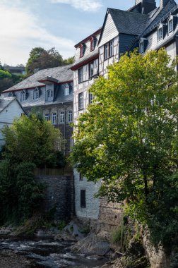 Nehrin kıvrımlarındaki eski renkli Alman şehri Monschau 'nun evleri ve caddeleri görünüyor ve tepelerin arasında saklanıyor, Eifel Ulusal Parkı, Almanya yazın.