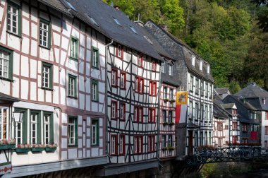 Nehrin kıvrımlarındaki eski renkli Alman şehri Monschau 'nun evleri ve caddeleri görünüyor ve tepelerin arasında saklanıyor, Eifel Ulusal Parkı, Almanya yazın.