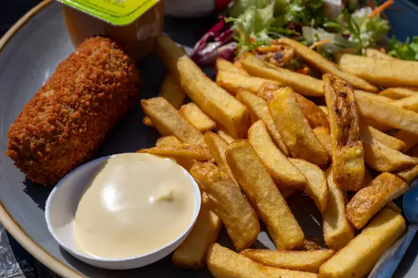 Dutch fast food, deep fried croquettes filled with ground beef meat and french fried potatoes chips served with mayonnaise, green salad, close up