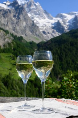 Savoy bölgesinden gelen beyaz Roussette de Savoie ve Vin de Savoie Fransız şarabı içerken yaz aylarında Hautes Alpes dağlarının zirvesinde kar manzaralı.