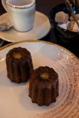 Fransa 'nın Bordeaux bölgesinin spesiyali olan rom ve vanilyalı Fransız pastası Canele, Fransız restoranında bir fincan siyah kahveyle beyaz tabakta servis edilir.