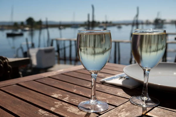 Güneşli bir günde Fransa 'nın Bordeaux kentindeki Arcachon Körfezi' nin tekneleri ve suları manzaralı çiftlik kafesinde beyaz şarap içmek.