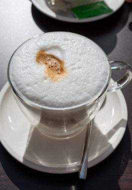 Açık kafede kremşantili sütlü taze İtalyan kahvesi içiyorum.