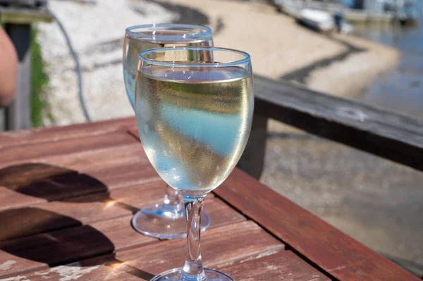 stock image Drinking of white wine at farm cafe in oyster-farming village, with view on boats and water of Arcachon bay, Cap Ferret peninsula, Bordeaux, France in sunny day